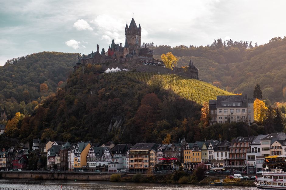 Cochem Castle crowns a scenic hilltop, offering panoramic views of the charming town below in autumn hues.